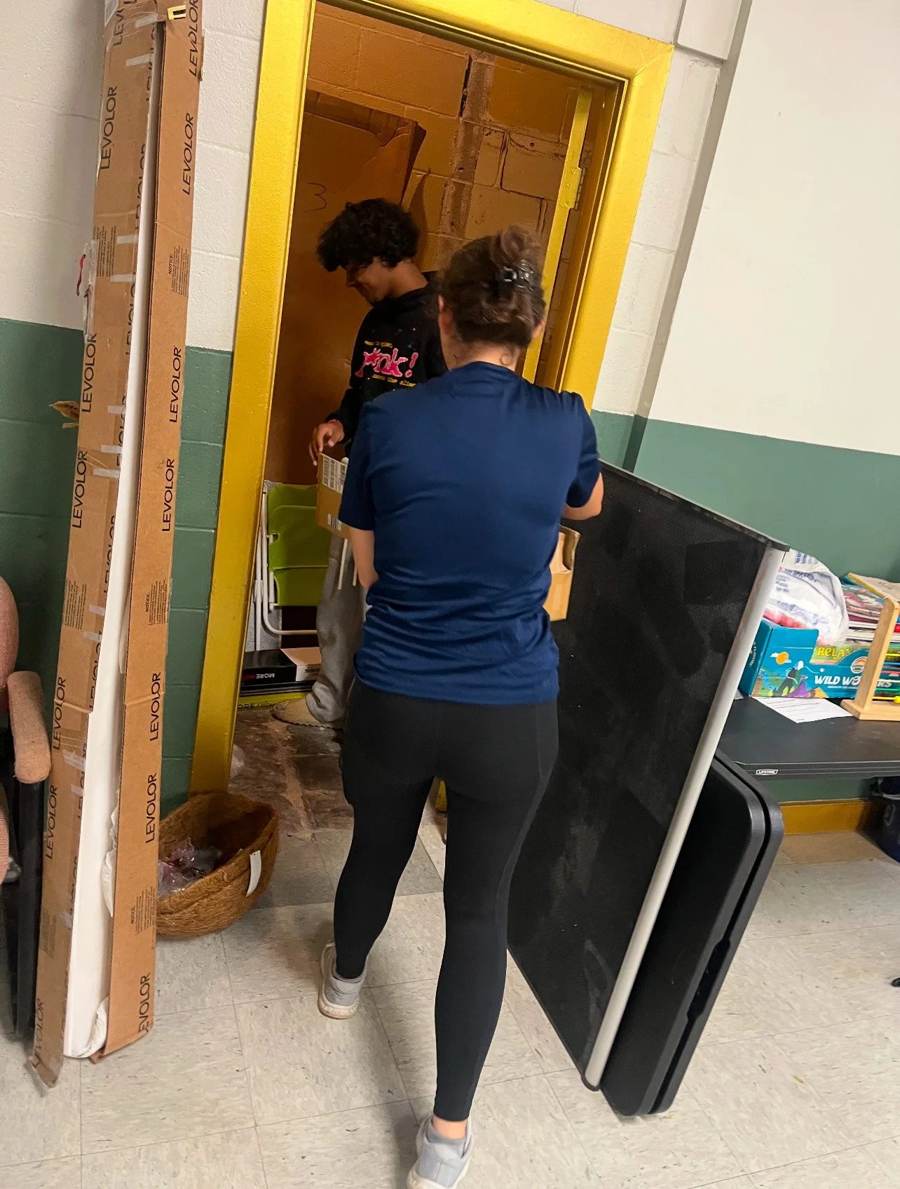 Volunteers carrying tables and supplies through a shelter doorway