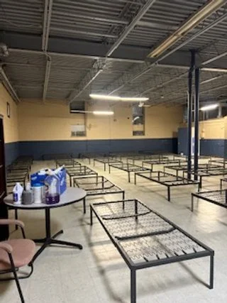 Shelter dormitory with rows of new bed frames ready for guests